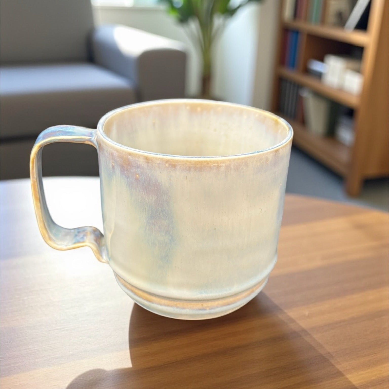 opalescent mug on a wooden side table in a cozy setting.