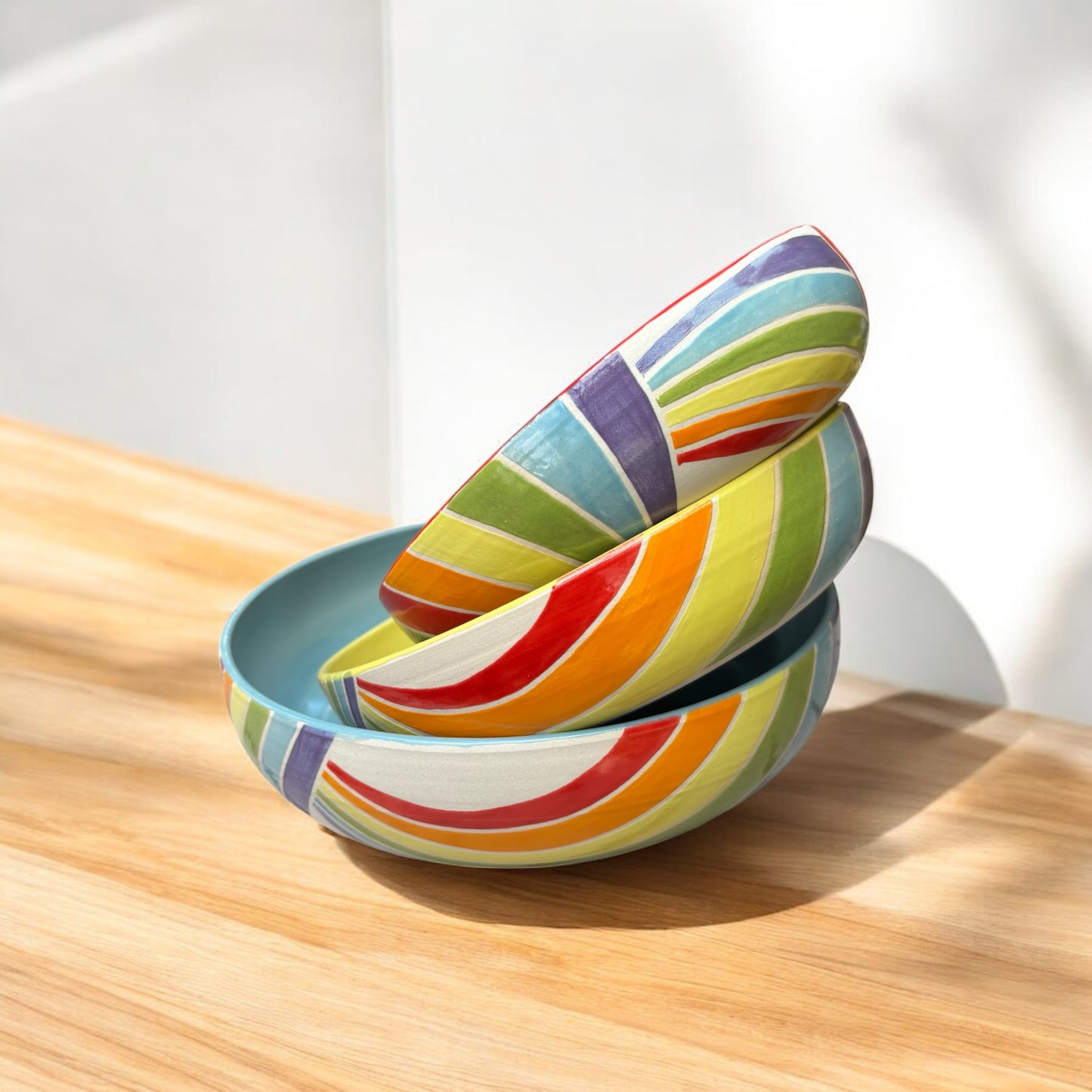 Colorful striped ceramic bowls on a wooden surface with a white background